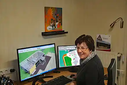 Contact person 5 The picture shows a woman seen from behind, turning over her shoulder toward the camera. She is sitting at a computer workstation.